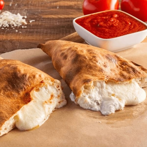 Two Ameci calzones with melted cheese spilling out, served with a side of marinara sauce.